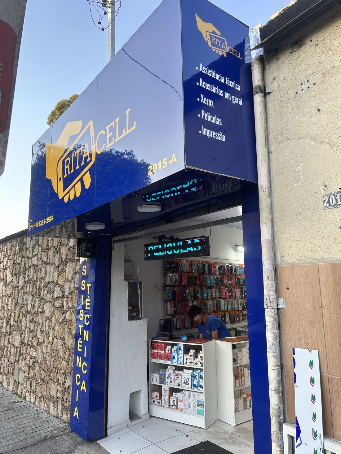 Fachada da loja RitaCell, com letreiro azul e amarelo